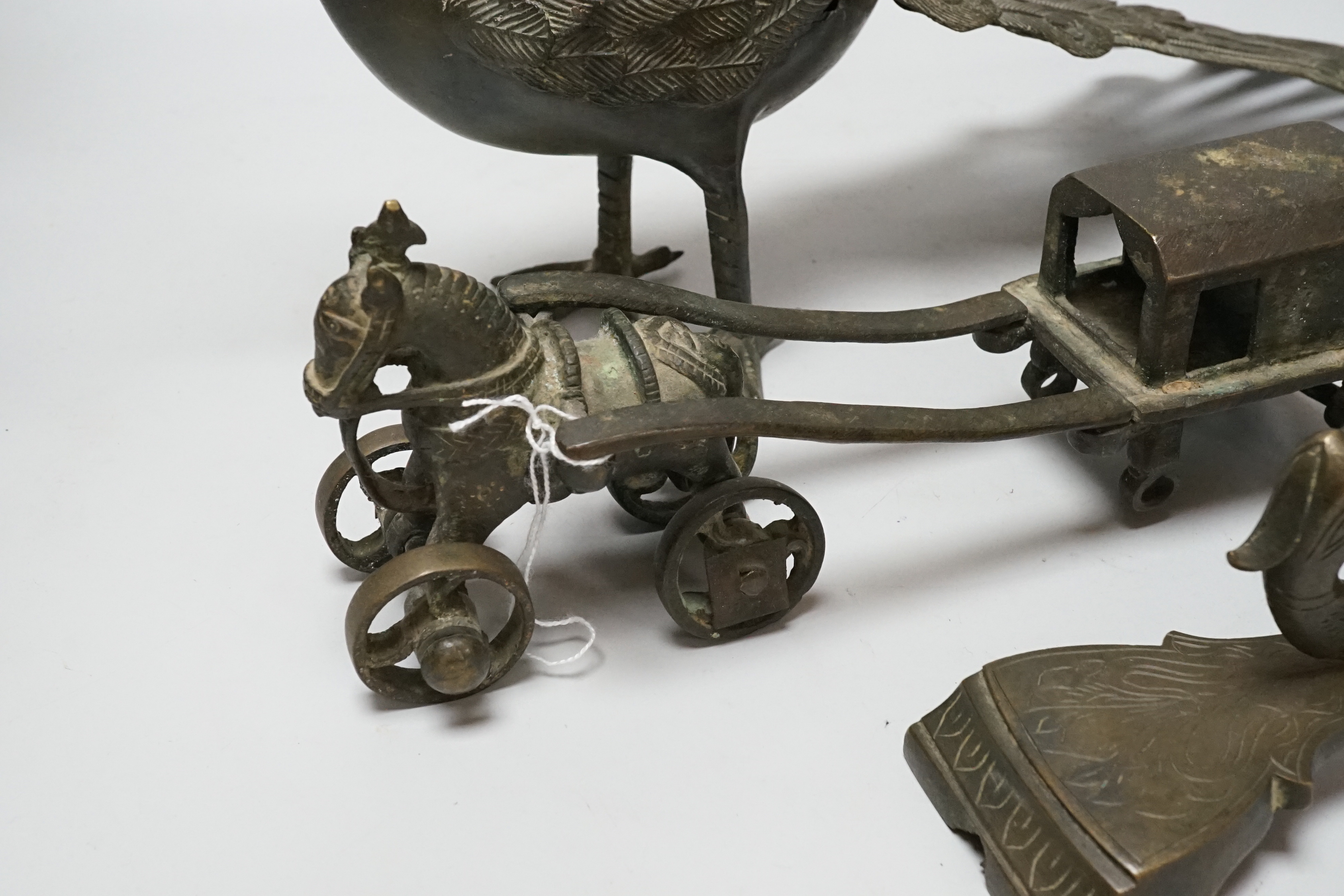 An Indian bronze horse and wagon (lacking one axle), an Indian bronze betel nut cutter and Indian bronze peacock, largest 53cm wide (3)